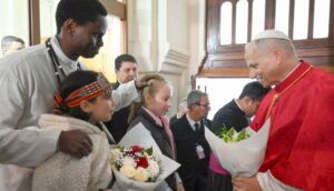 Il Papa saluta un uomo e due ragazze nella basilica cattolica di Algeri.